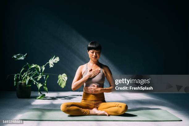 japanese woman finding serenity: yoga for mental wellness - woman hand crossed stockfoto's en -beelden