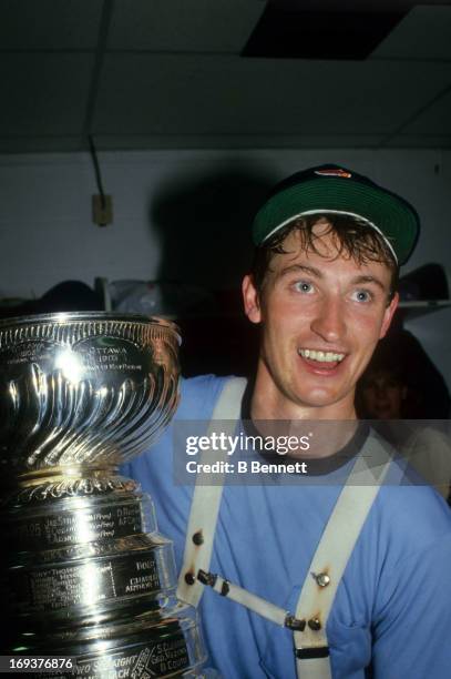 Wayne Gretzky of the Edmonton Oilers celebrates in the locker room with the Stanley Cup Trophy after the Oilers defeated the New York Islanders in...