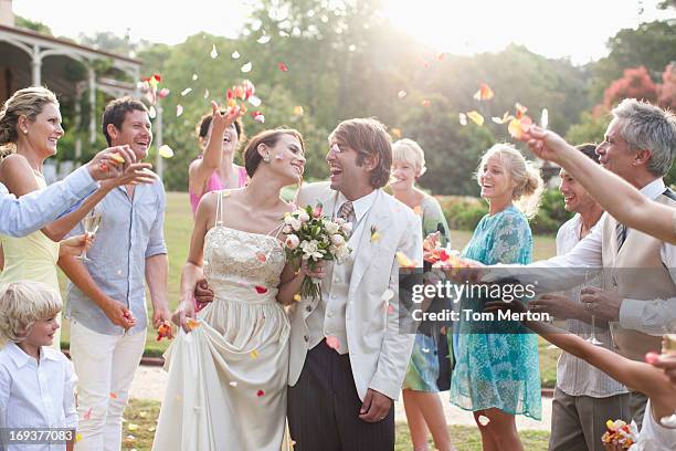 huéspedes tirando pétalos de rosa sobre la novia y novio - invitado de boda fotografías e imágenes de stock