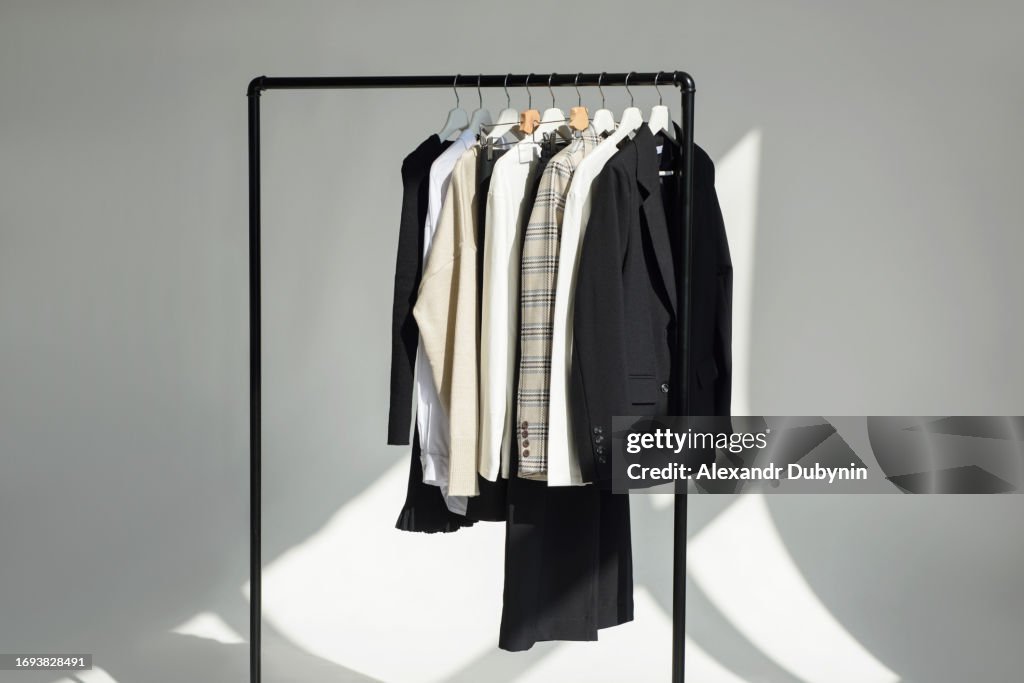 A lot of different wardrobe clothes hang on hangers on a rail. Concept for selling clothes.