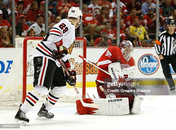 Cory Emmerton of the Detroit Red Wings makes a third period save next to Bryan Bickell of the Chicago Blackhawks in Game Four of the Western...