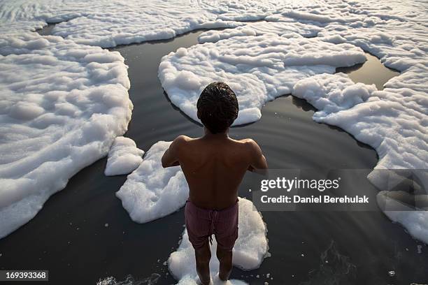 Indian men bathe in an industrial waste-foam polluted section of the Yamuna River, on the outskirts of New Delhi on May 24, 2013 in New Delhi, India....