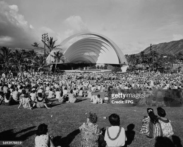 View over the heads of the audience towards the stage with a hula show in progress at the Waikiki Shell, an outdoor concert venue, in Kapiolani Park,...
