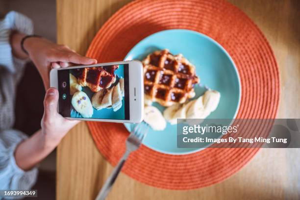 teenage girl taking photo of her homemade dessert with smartphone at dining table at home - place mat stock pictures, royalty-free photos & images