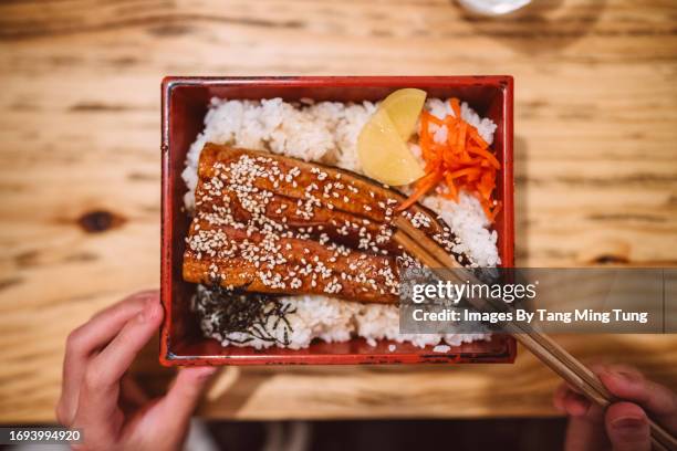 directly above view of a woman eating an eel bento with chopsticks in a japanese restaurant - bento box stock pictures, royalty-free photos & images
