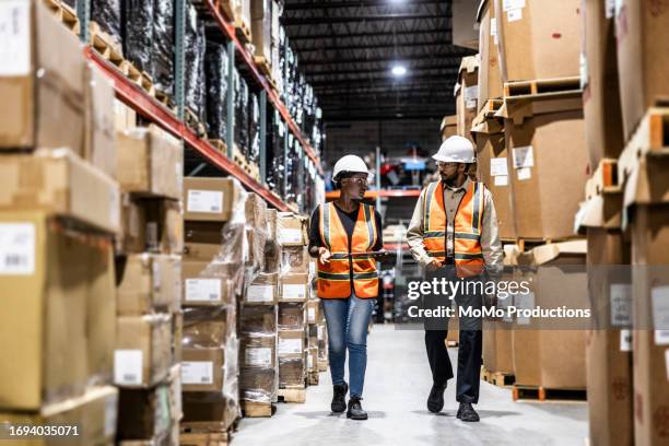 warehouse employees walking in aisle of warehouse - vraag en aanbod stockfoto's en -beelden