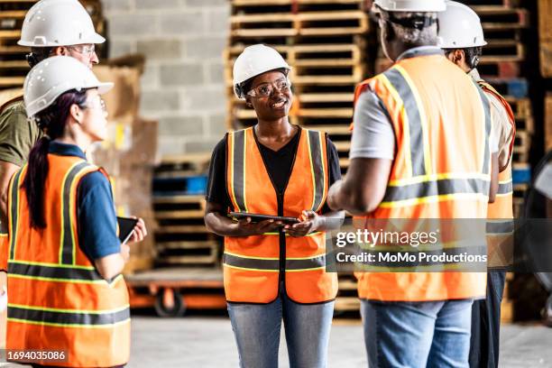 female warehouse supervisor speaking with a group of employees - occupational health and safety stock pictures, royalty-free photos & images