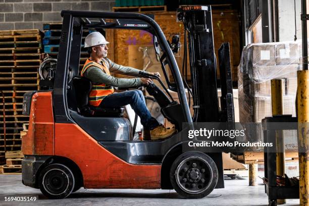 warehouse employee driving forklift - gabelstapler amerika stock-fotos und bilder