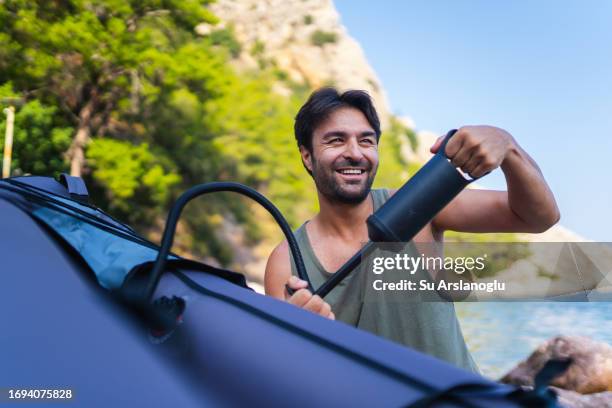 macho adulto inflando su kayak - bote neumático fotografías e imágenes de stock
