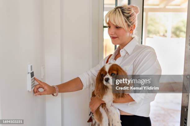 beautiful woman leaving her house and locking the door using a home automation system - animal leg stockfoto's en -beelden