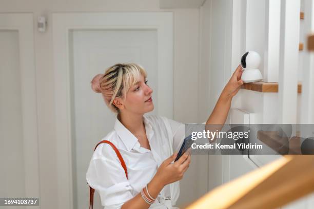 beautiful woman leaving her house and locking the door using a home automation system - alarm stockfoto's en -beelden
