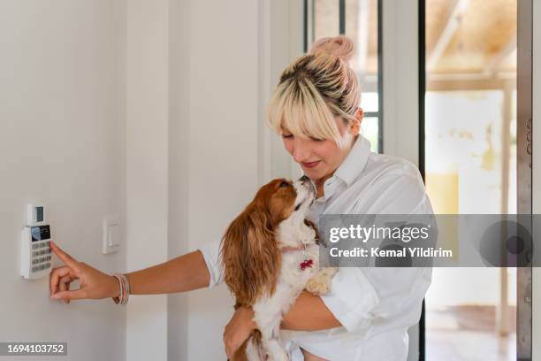 hermosa mujer saliendo de su casa y cerrando la puerta con un sistema de domótica - alarma de seguridad fotografías e imágenes de stock
