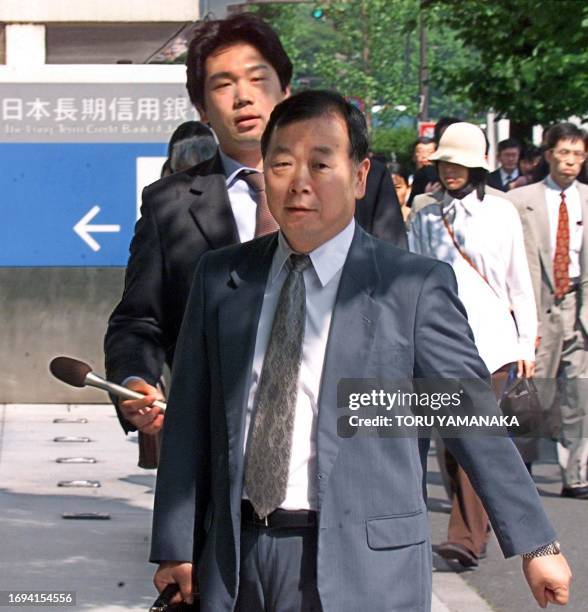 Reporter tries to interview a bank clerk of the collapsed Long-Term Credit Bank of Japan in front of LTCB headquarters in Tokyo 09 June 1999. Tokyo...
