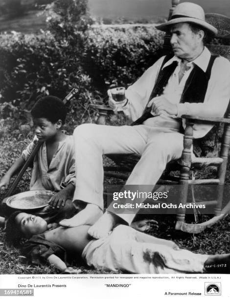 James Mason resting his arthritic feet on slave in a scene from the film 'Mandingo', 1975.