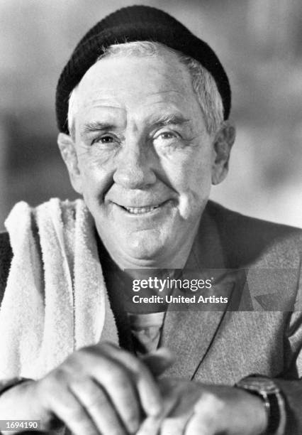 American actor Burgess Meredith wears a hat and a towel over his shoulder in a promotional portrait for the film, 'Rocky,' directed by John G....