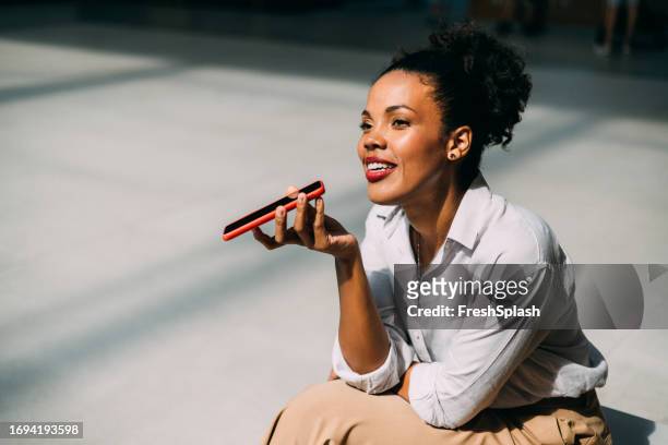 a happy beautiful cuban businesswoman looking away while talking on her mobile phone outdoors - red background stock pictures, royalty-free photos & images