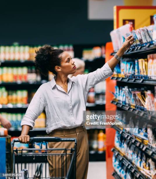 a serious beautiful cuban woman shopping at the supermarket - consumerism stock pictures, royalty-free photos & images