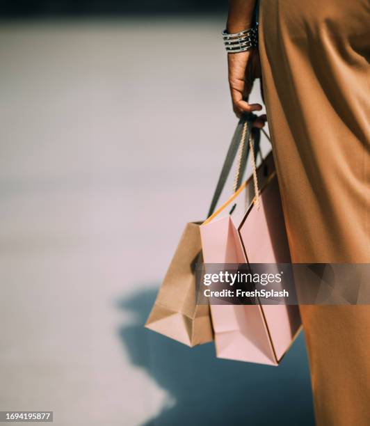 a close up view of an unrecognizable beautiful cuban woman holding paper bags after going shopping - shopping bag in hand stockfoto's en -beelden