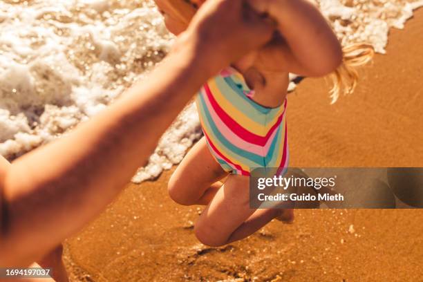 mother and her little girl playing together at the beach. - sunburn tourist stock-fotos und bilder