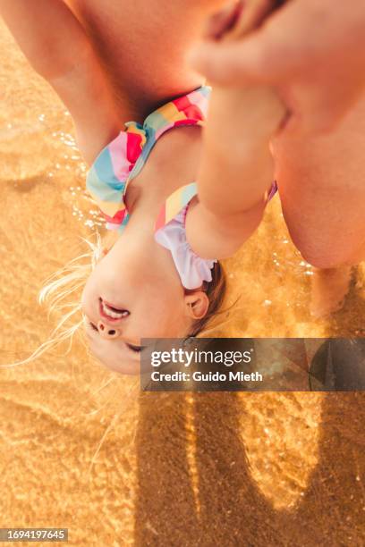 mother and her daughter playing together at the beach. - sunburn tourist stock-fotos und bilder