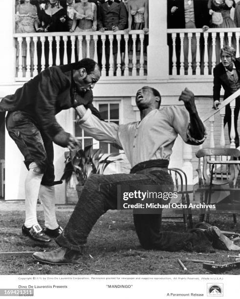 Kneeling Ken Norton fights as his master Perry King watches in a scene from the film 'Mandingo', 1975.