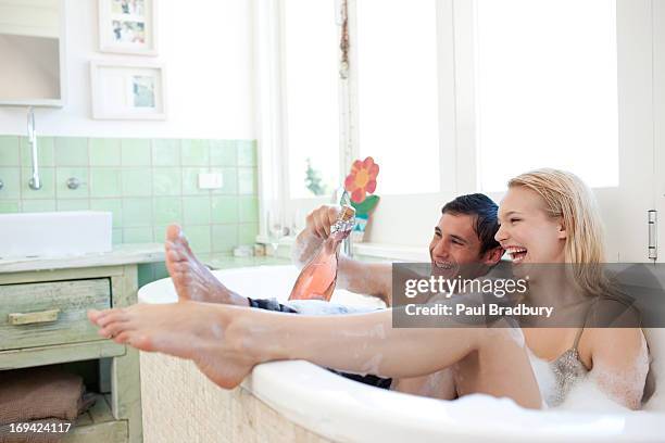 paar in kleidung trinken champagner in der badewanne - bad relationship stock-fotos und bilder