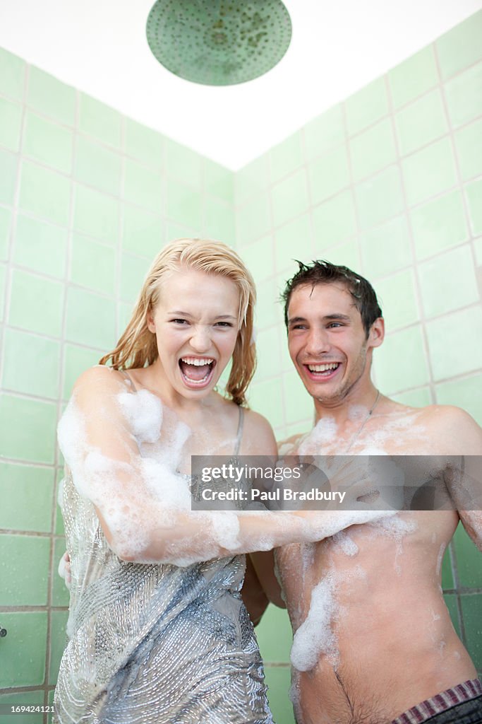 Couple in bathtub covered with soap suds 