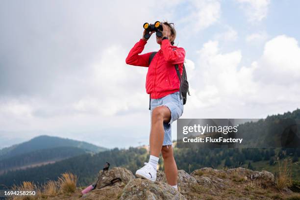 female hiker from the observation point on mountain observing nature with binoculars - viewing binoculars stock pictures, royalty-free photos & images