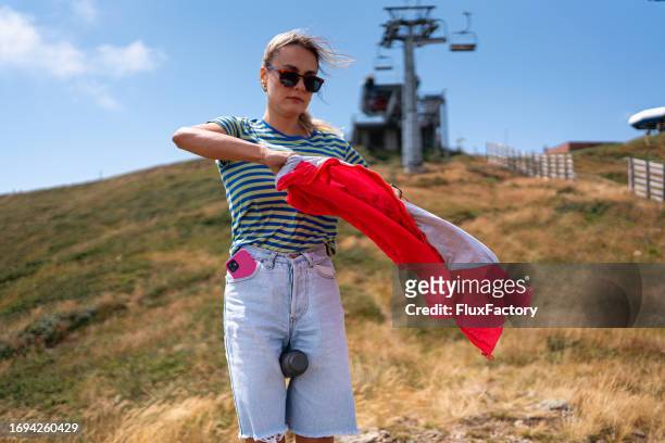 female tourist taking off her jacket, during an mountain hike - taking off coat stock pictures, royalty-free photos & images