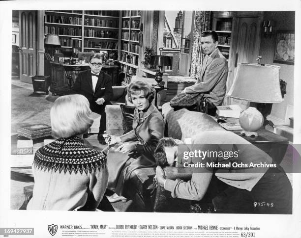 Debbie Reynolds, Barry Nelson, and Michael Rennie gathered around couch in a scene from the film 'Mary, Mary', 1963.