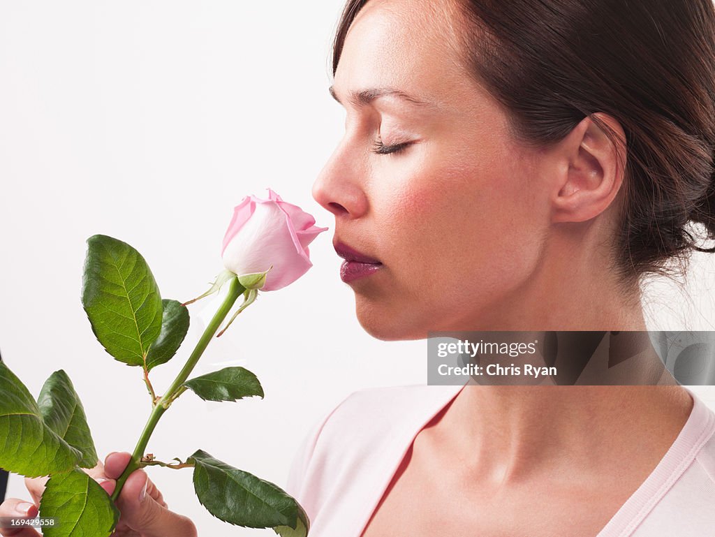 Plano aproximado de mulher a cheirar as Rosa Rosa