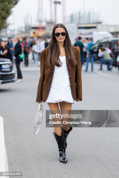 Gabrielle Caunesil Pozzoli wears brown wild leather jacket, white dress, white bag, black cowboy boots outside Prada during the Milan Fashion Week -...