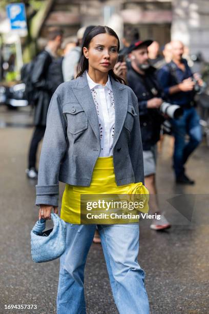 Guest wears yellow skirt, denim jeans, grey blazer, blue Bottega Veneta bag outside Emporio Armani during the Milan Fashion Week - Womenswear...