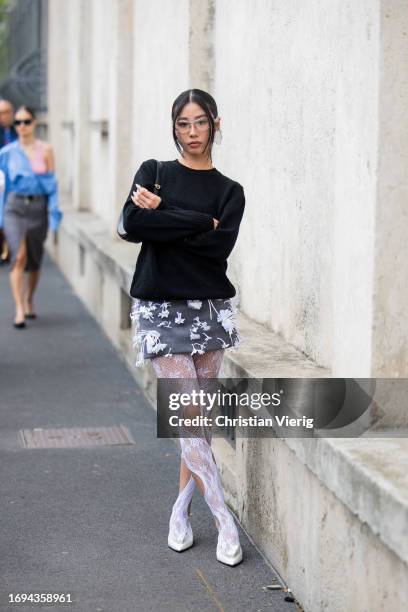 Guest wears black skirt, jumper, bag, laced tights outside Prada during the Milan Fashion Week - Womenswear Spring/Summer 2024 on September 21, 2023...