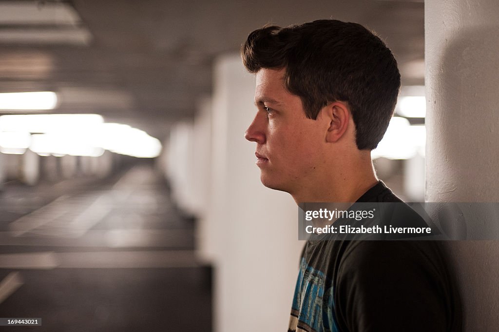 Young man waits in an empty car park