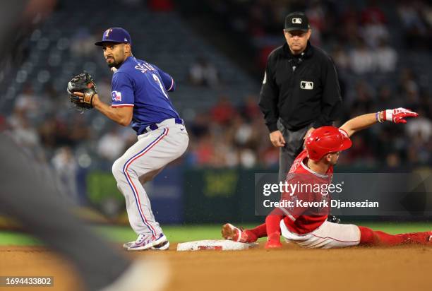 Marcus Semien of the Texas Rangers looks to throw to first base after forcing out Zach Neto of the Los Angeles Angels at second base in an attempt to...