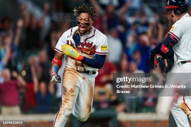 Ronald Acuña Jr. #13 of the Atlanta Braves celebrates after scoring the game-winning run in the tenth inning against the Chicago Cubs at Truist Park...