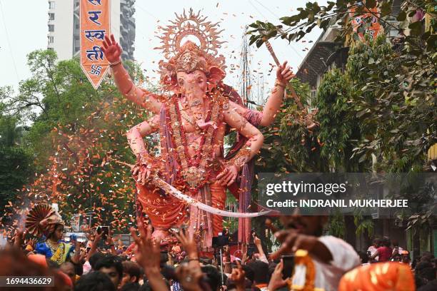 Large idol of the elephant-headed Hindu God Lord Ganesha is showered with flower petals during a procession before immersing the idol in the Arabian...