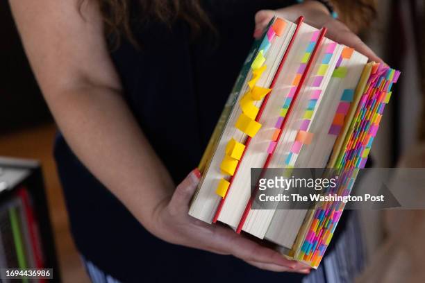 Jennifer Petersen holds a stack of books that she has challenged, "sexual content" marked with dozens of colorful sticky notes, at her home on...