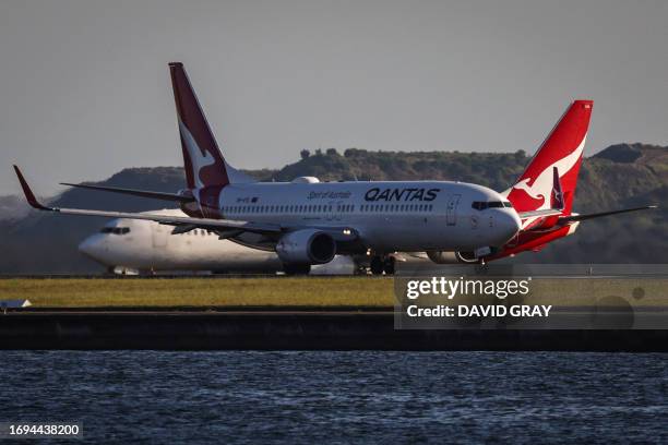 Qantas Boeing 737-800 plane travels down the runway as another Qantas plane waits on the tarmac at SydneyÕs Kingsford Smith international airport on...