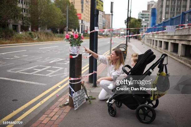 Mother and child look at tributes left on the kerb for the murdered schoolgirl on September 28, 2023 in Croydon, England. A 15-year-old girl was...