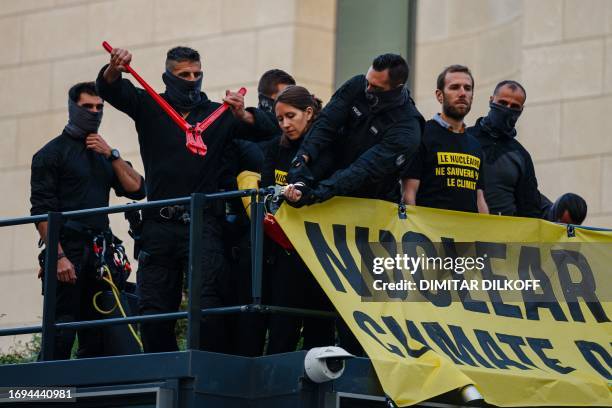 Police officer removes a handcuffs from a Greenpeace activist's hand during an anti-nuclear protest prior to the opening of a nuclear energy...