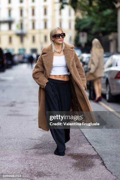 Caro Daur is seen wearing Max Mara brown sunglasses, a gold chain necklace, a white belly-off tank top, a teddy-bear long beige coat and low waist...