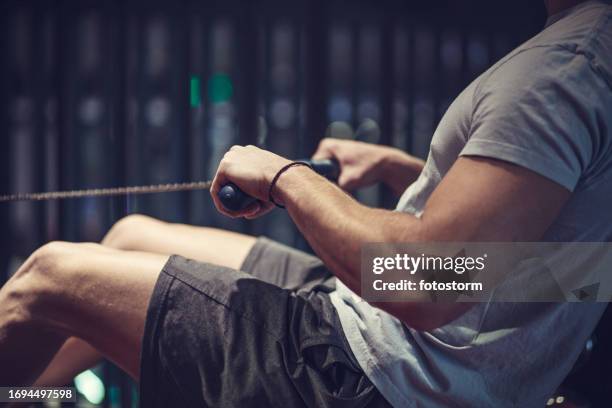 athletic man doing cardio work out on a rowing machine - cardio machine stock pictures, royalty-free photos & images