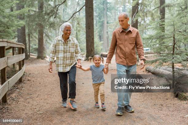 vibrant multiracial senior couple hiking with their young granddaughter - development camp stock pictures, royalty-free photos & images