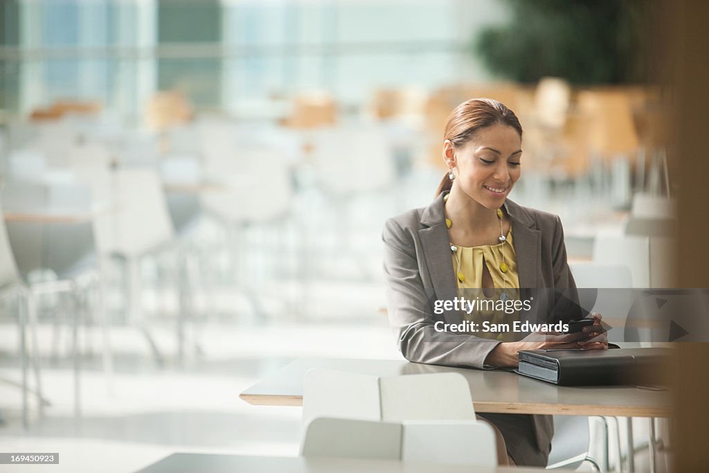 Business Woman using phone sitting at cafeteria table