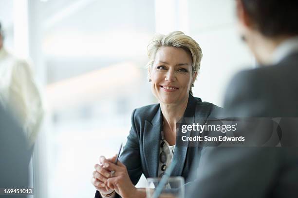 smiling businesswoman in meeting - mature businessman stock pictures, royalty-free photos & images