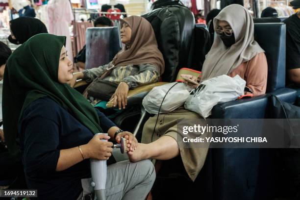 Woman massages a customer's foot at Tanah Abang Market, Southeast Asia's largest wholesale shopping center for garment and textile, in Jakarta on...