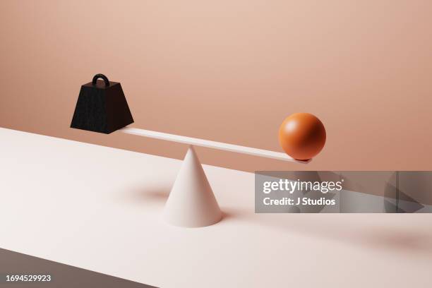 large orange sphere and metal weight - balance photos et images de collection
