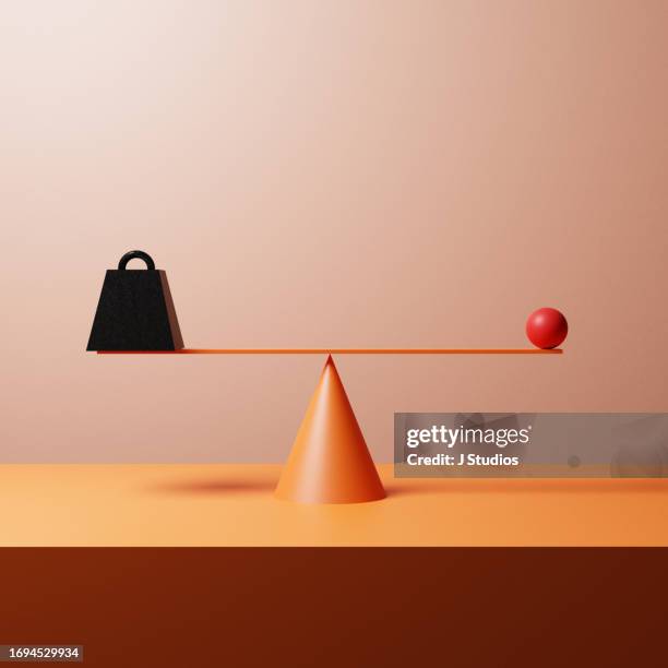 metal weight balancing against a red ball - side by side comparison stock pictures, royalty-free photos & images